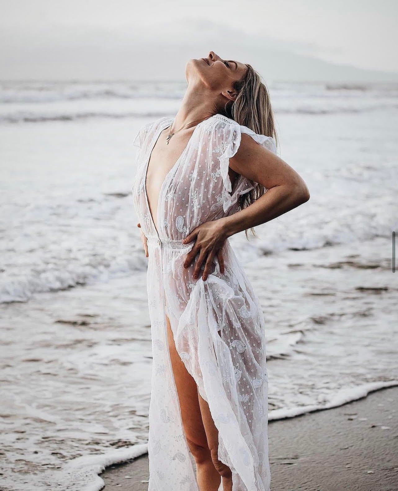 Leah on the beach in a white dress, head thrown back