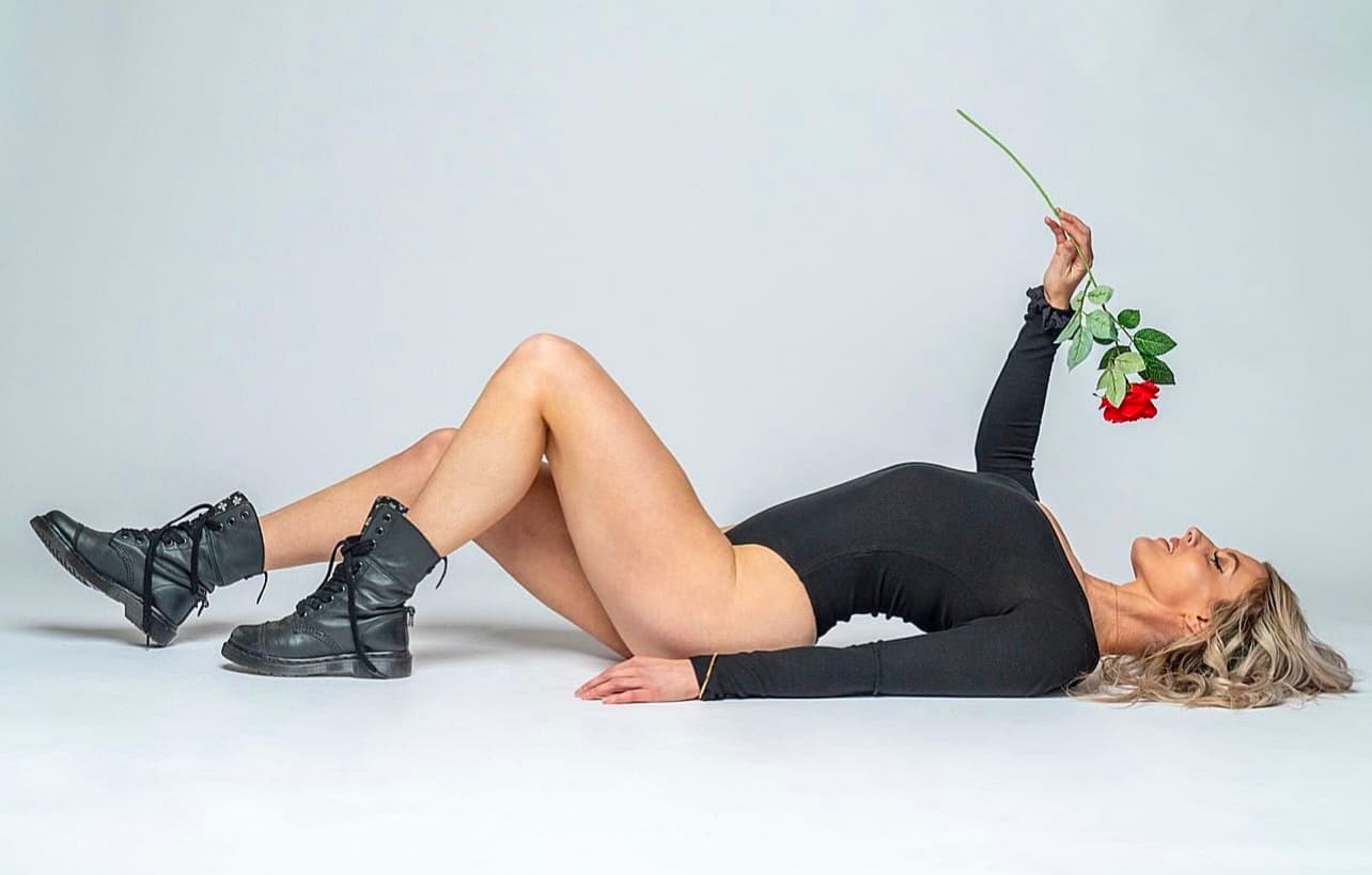 Leah lying on a white floor holding a red rose